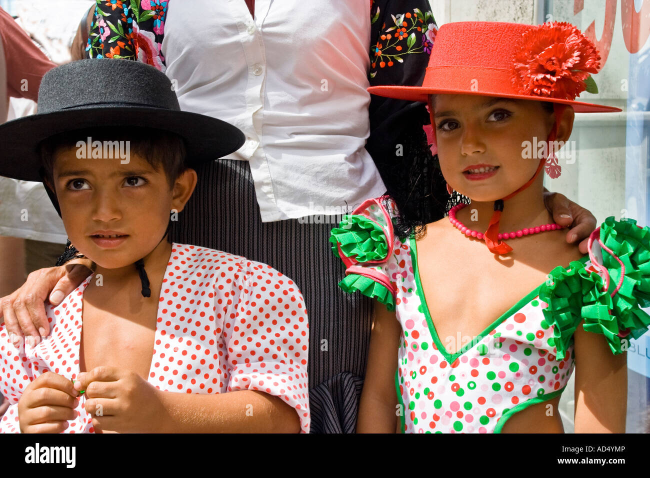 Brother and sister, with mother behind, in traditional costume for the annual feria, or fair, in Malaga city, Andalusia, Spain. Stock Photo