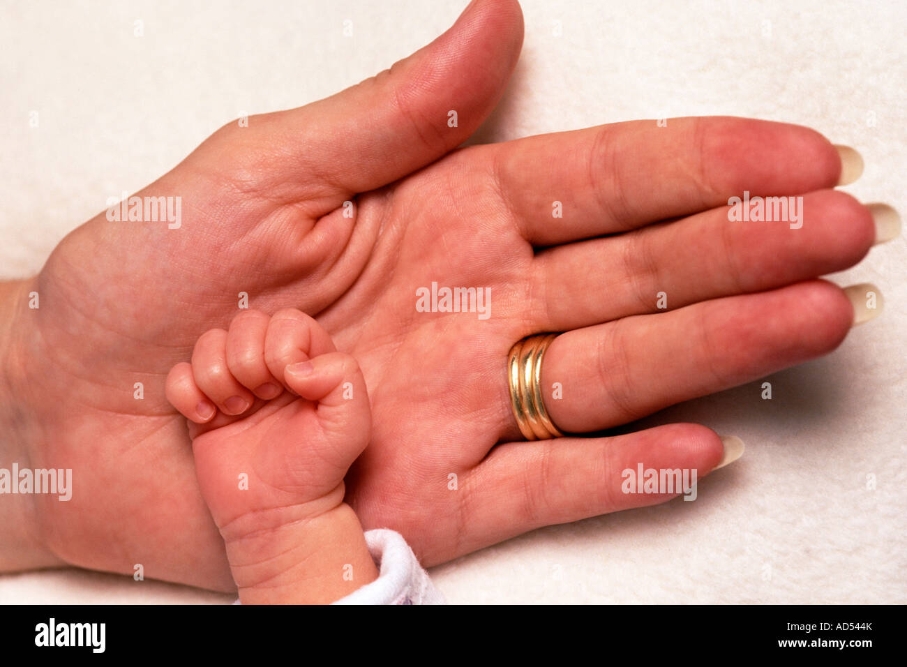 A baby girl's hand lies cradled in her mother's open palm. Stock Photo