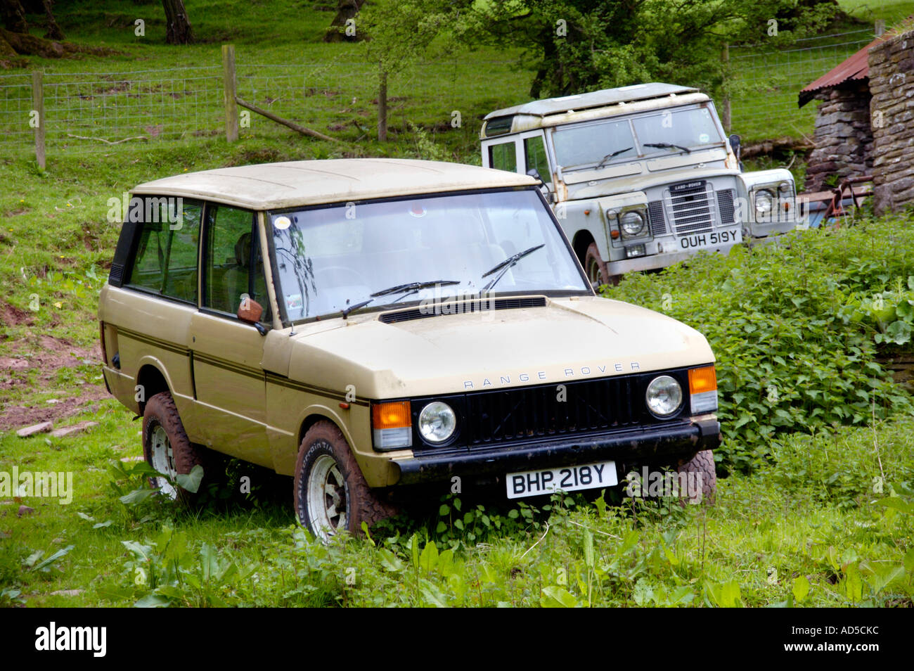 Old Range Rover and Land Rover Defender on farmland near Abergavenny Monmouthshire South Wales UK Stock Photo