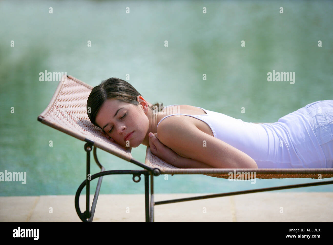 Young woman relaxing on a deckchair by the swimming pool Stock Photo ...