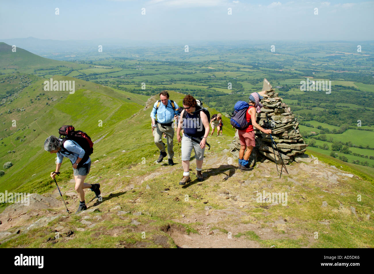 Guided walking group reach the cairn at top of Dragons Back in the Black Mountains near Pengenffordd Powys South Wales UK Stock Photo