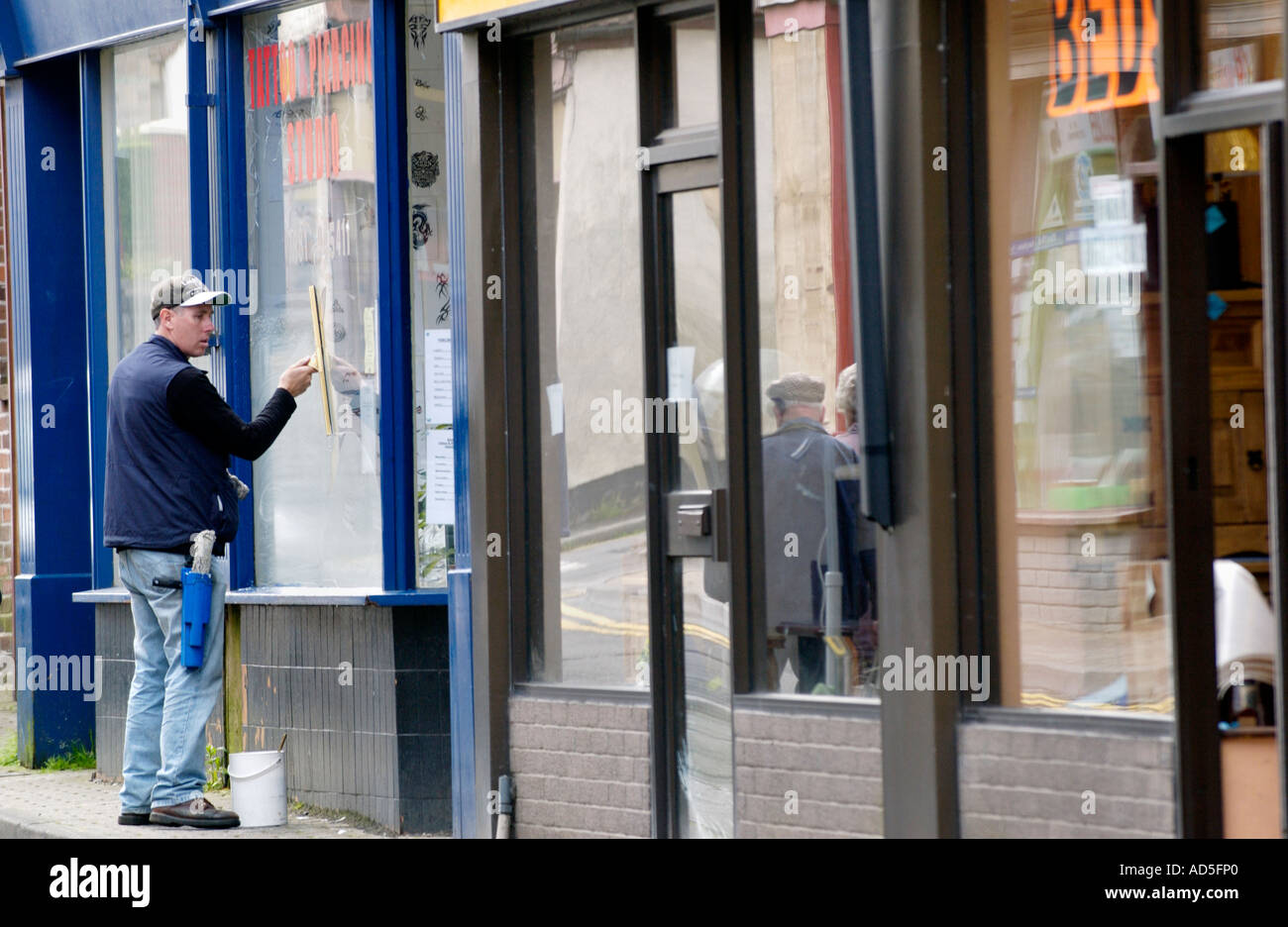 Self employed window cleaner cleaning shop window in Abertillery Blaenau Gwent South Wales Valleys UK Stock Photo