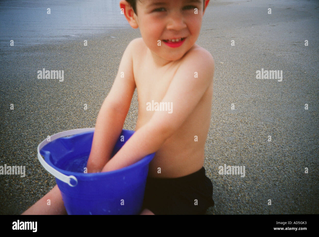 Little boy playing in bucket of water Stock Photo Alamy