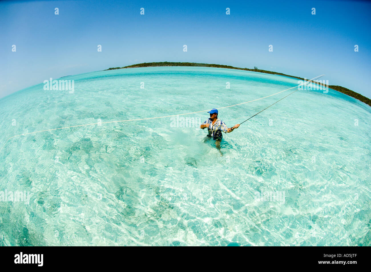 GREATER EXUMA  BAHAMA S Fly fisherman casting for Bone fish in emerald green water Fish Eye Panorama Atlantic Ocean MR Stock Photo