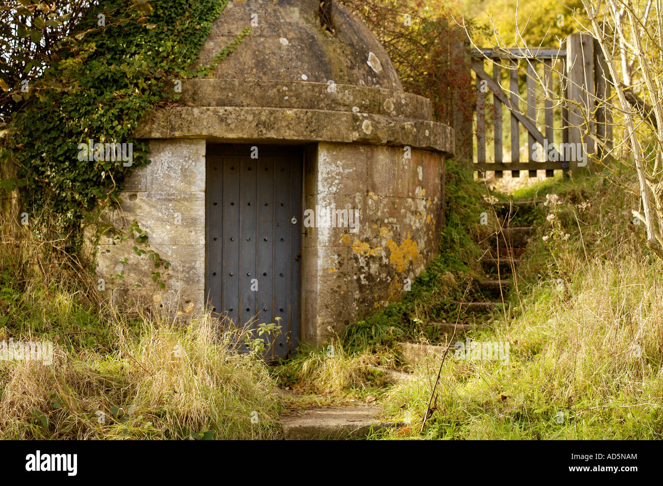 A stone icehouse with steps leading up to a wooden gate Stock Photo
