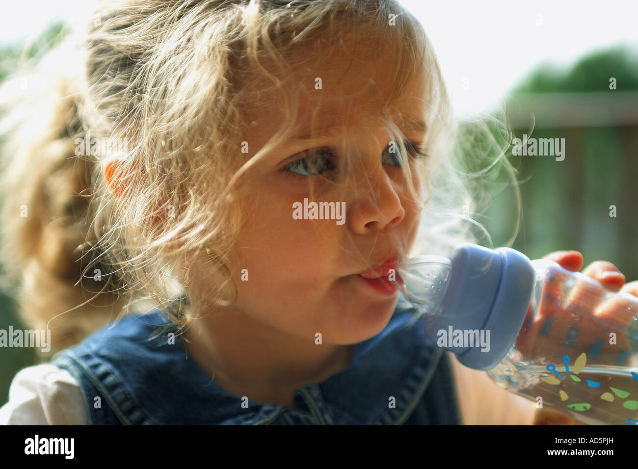 Toddler girl drinking water from the baby bottle Stock Photo