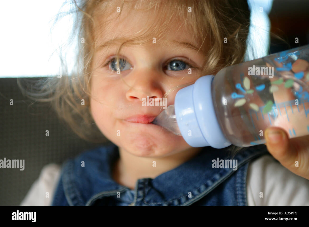 Little girl drinking water from a baby's bottle Stock Photo Alamy