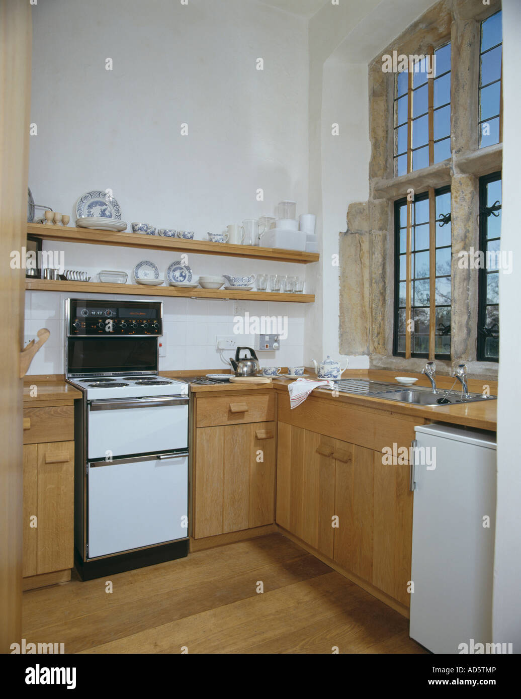 Shelves above oven in kitchen with wooden units and window with stone