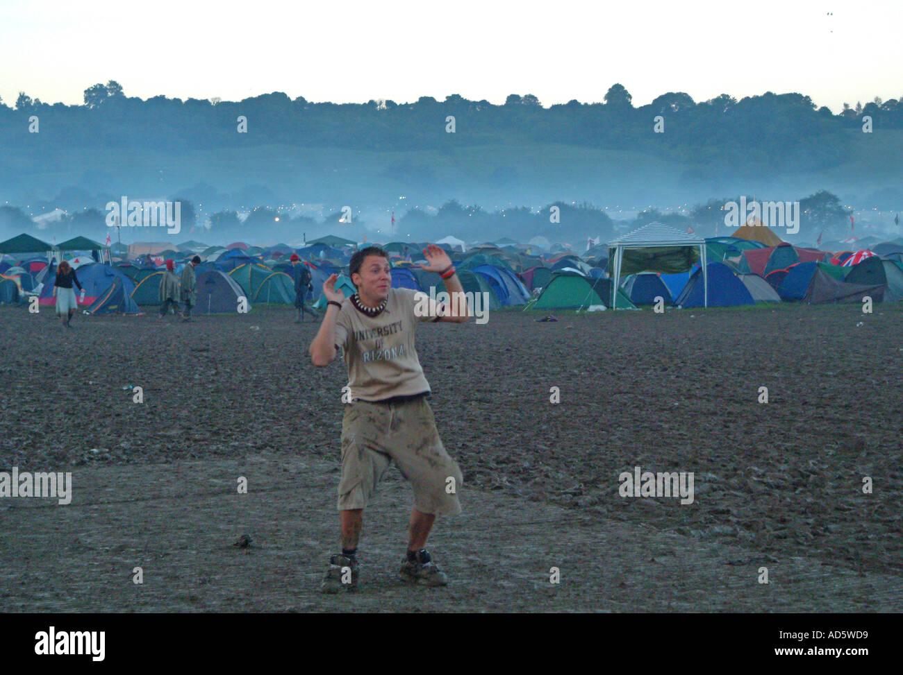 A young Glastonbury raver dancing in the mud in the early hours of the morning. Somerset, UK Stock Photo