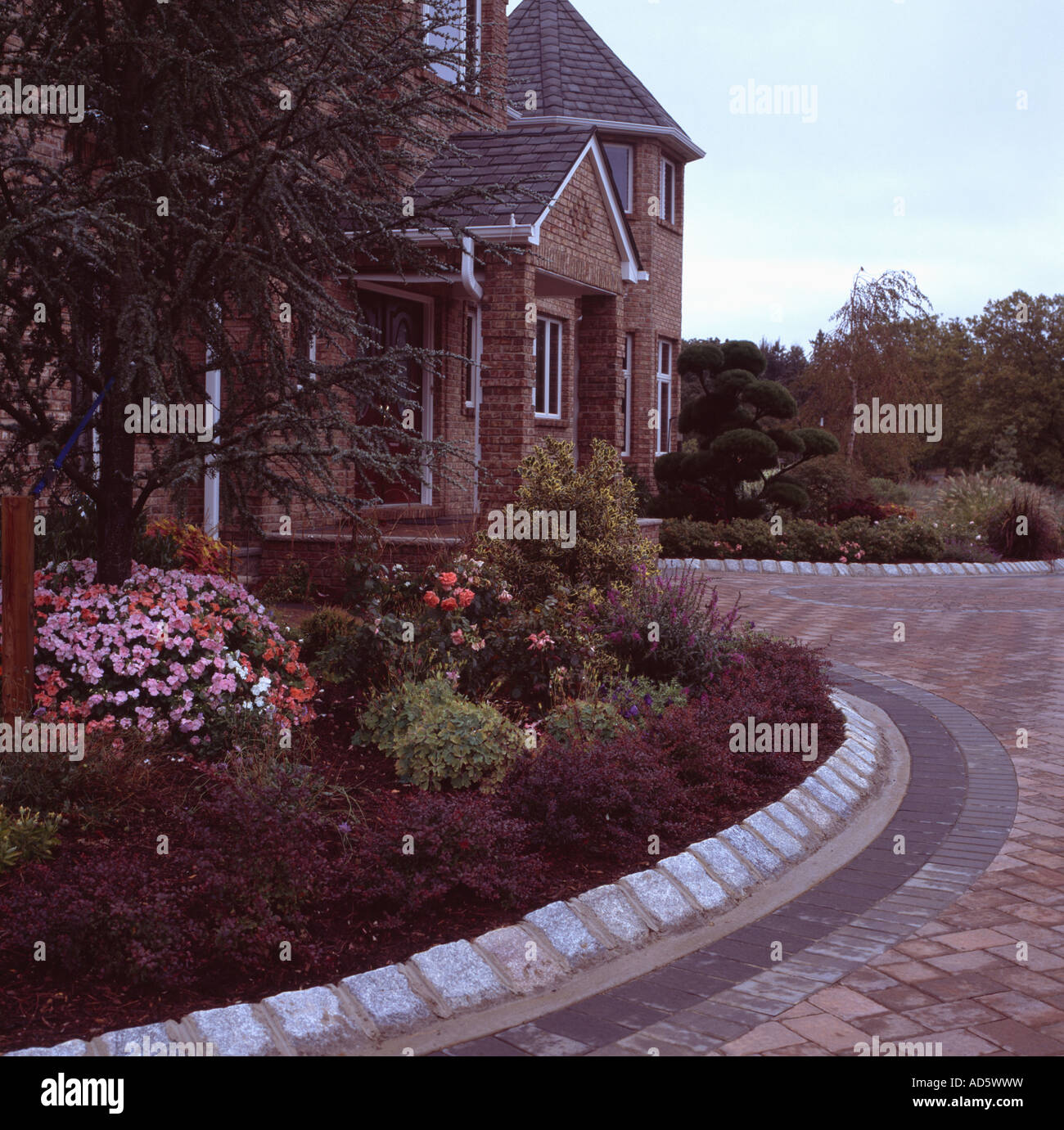 Stone edging around curved garden border in front of traditional new