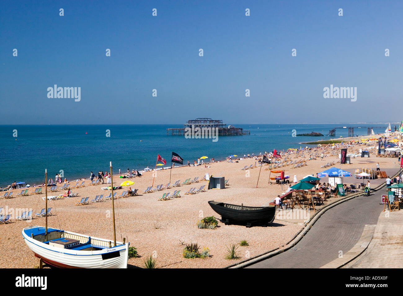 Summer On Brighton Beach UK Showing Abandoned West Pier In Distance summer-on-brighton-beach-uk-showing-abandoned-west-pier-in-distance