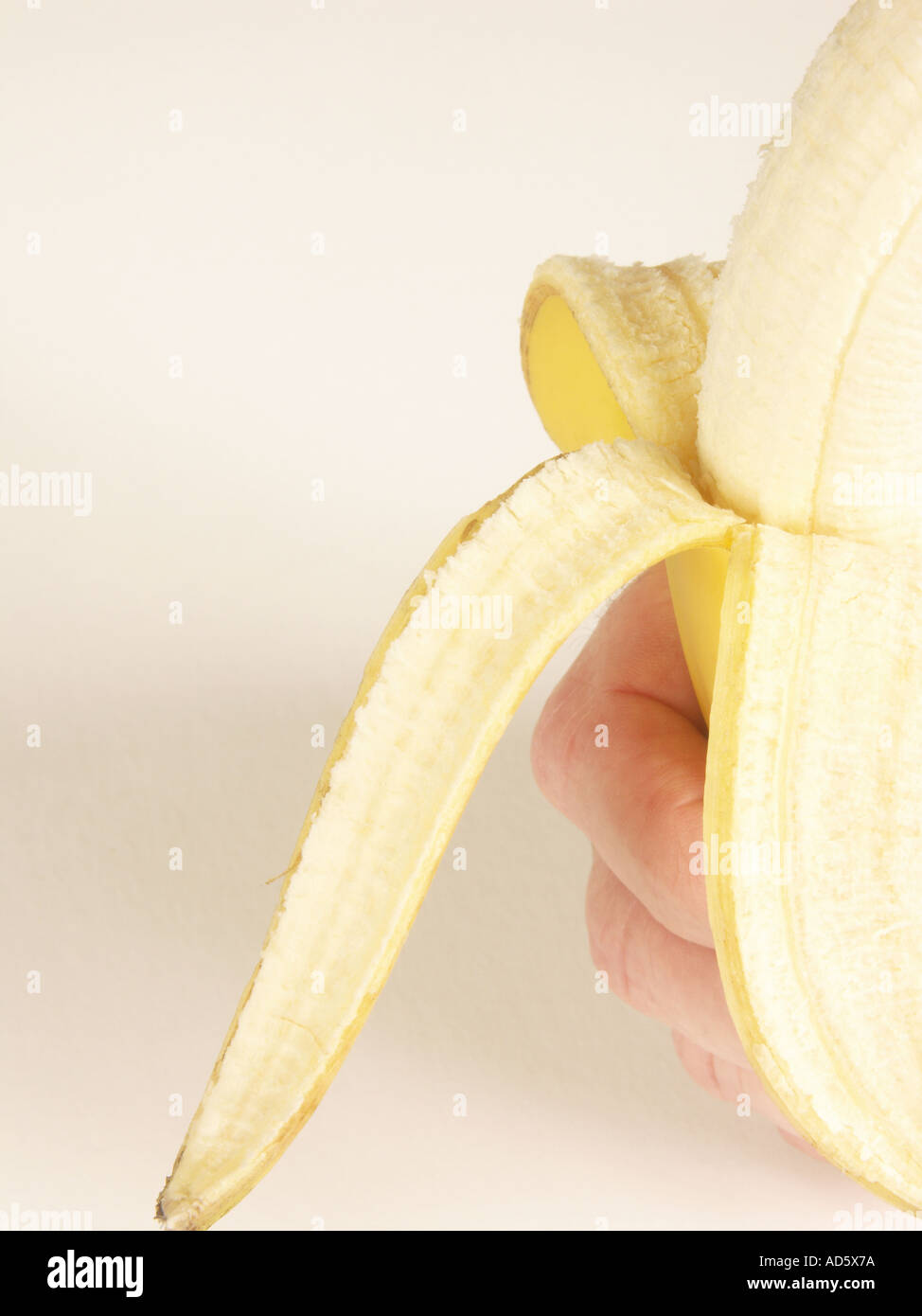 Hand with half peeled banana Stock Photo