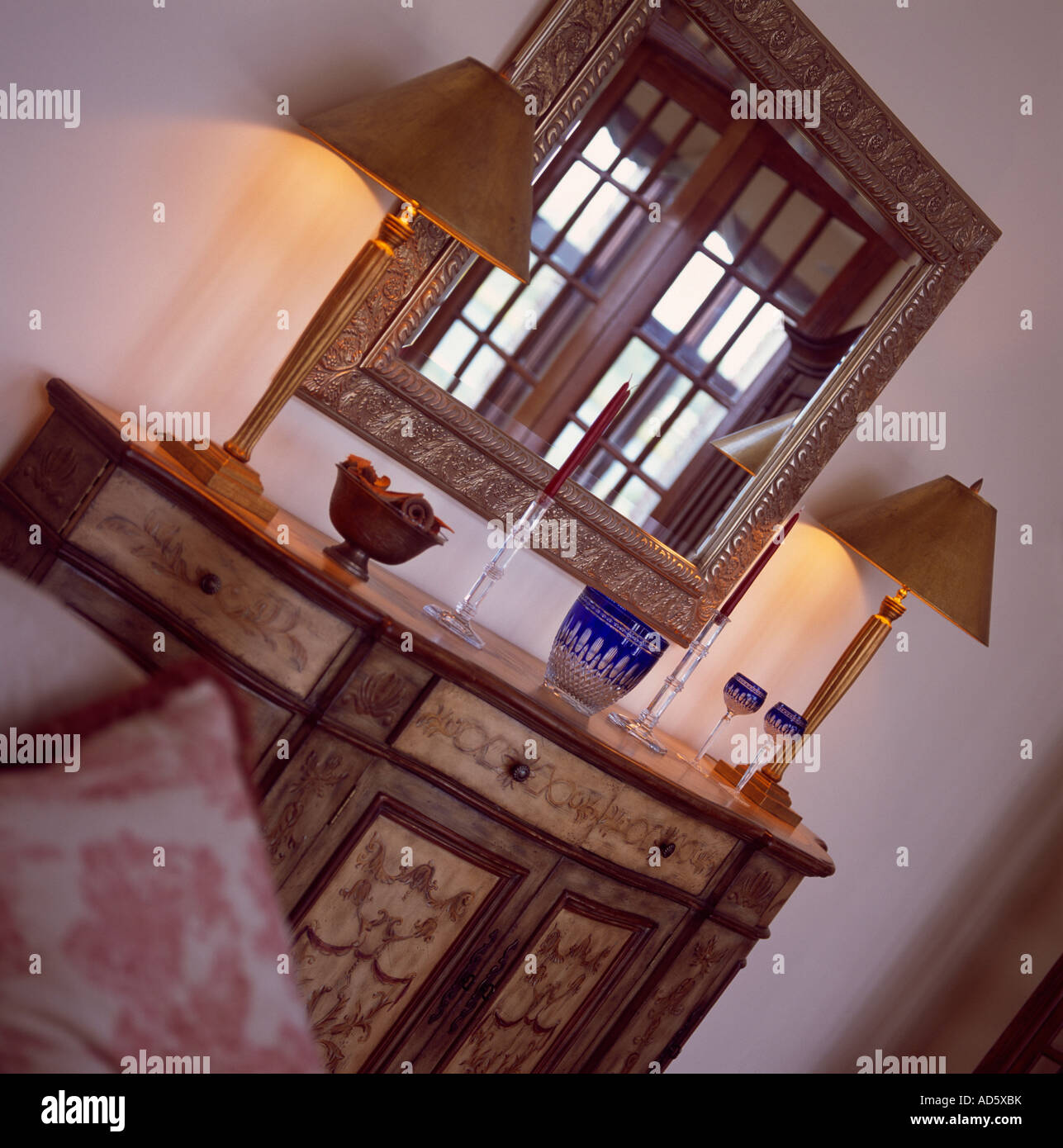 Slanted view of mirror above antique painted cupboard with lighted