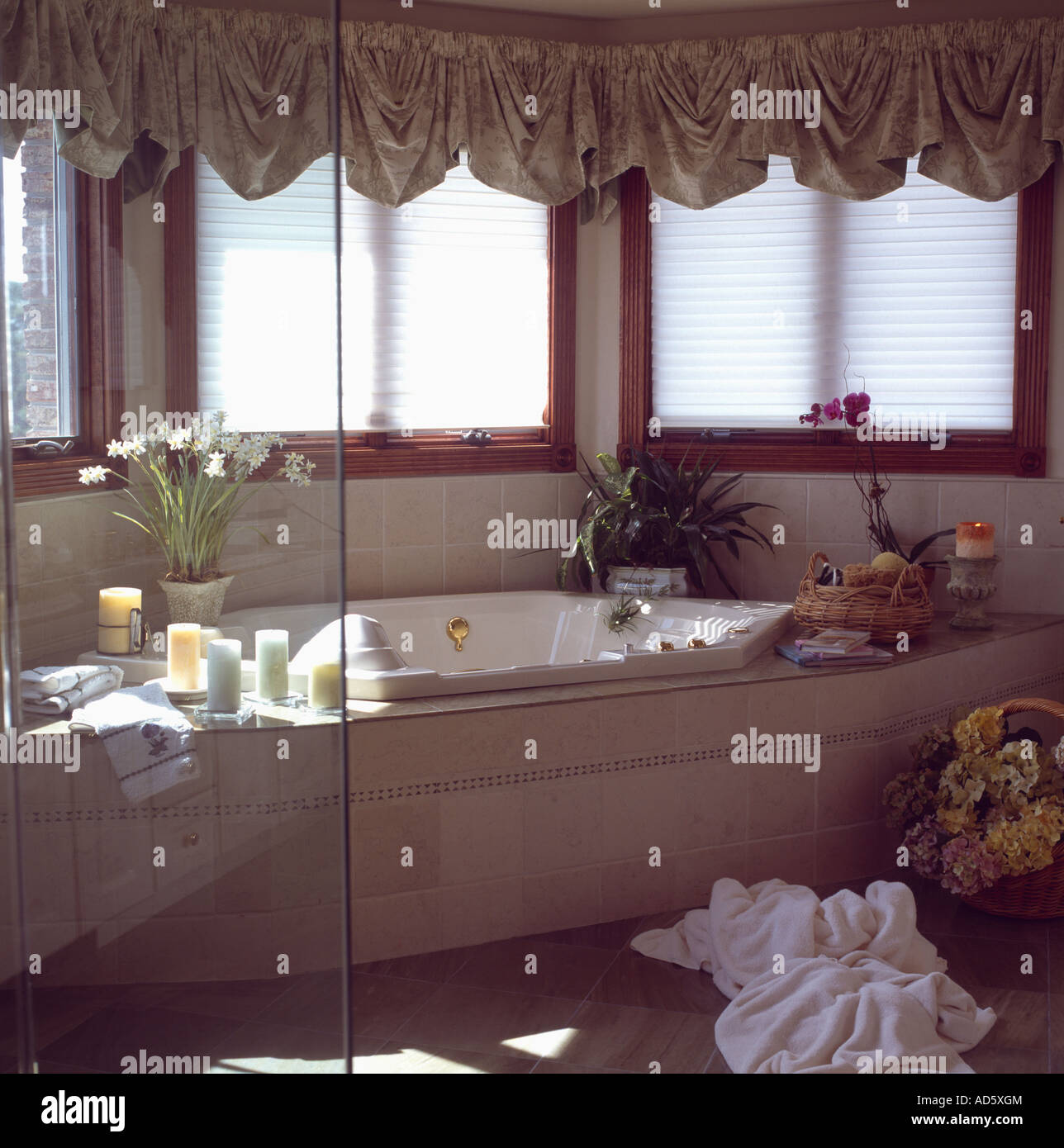 Grey festoon blinds at windows above bath and white towels on floor of