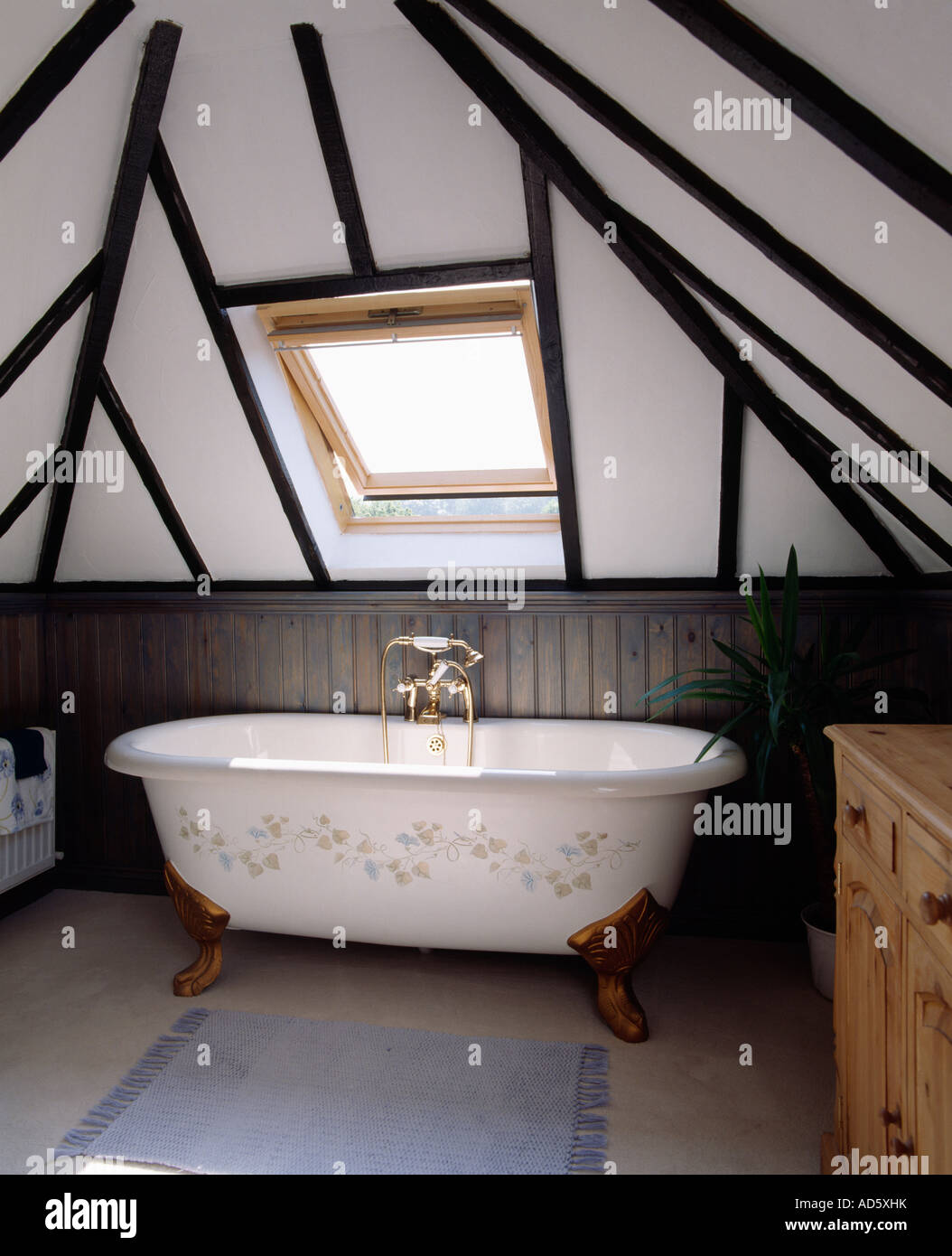 White freestanding clawfoot bath with floral stencil below velux window in  beamed attic bathroom Stock Photo - Alamy