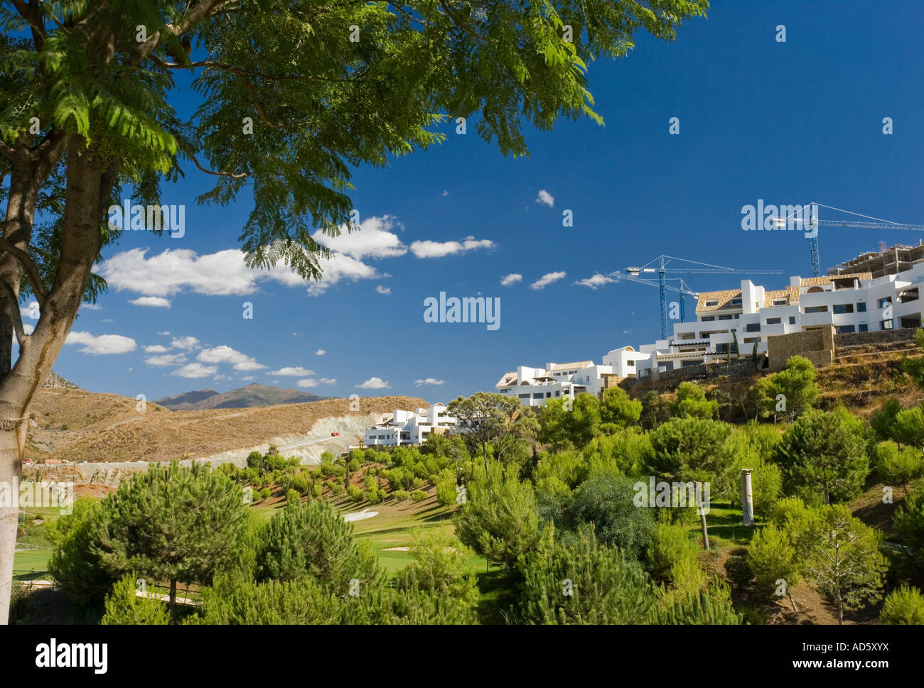Modern white Spanish holiday village on wooded hilltop with mechanical ...