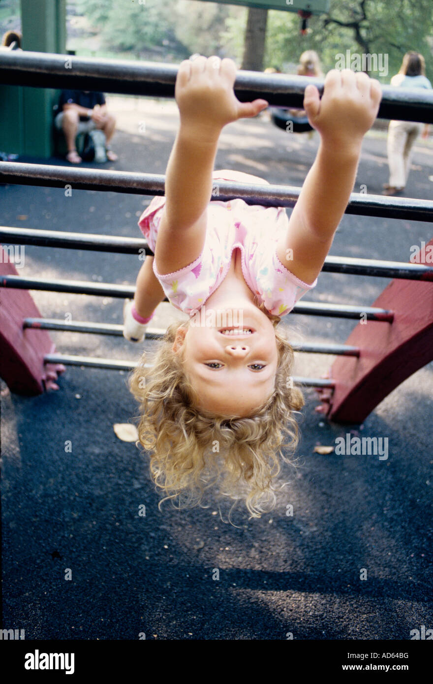 Young girl hanging upside down on playground ladder Stock Photo - Alamy