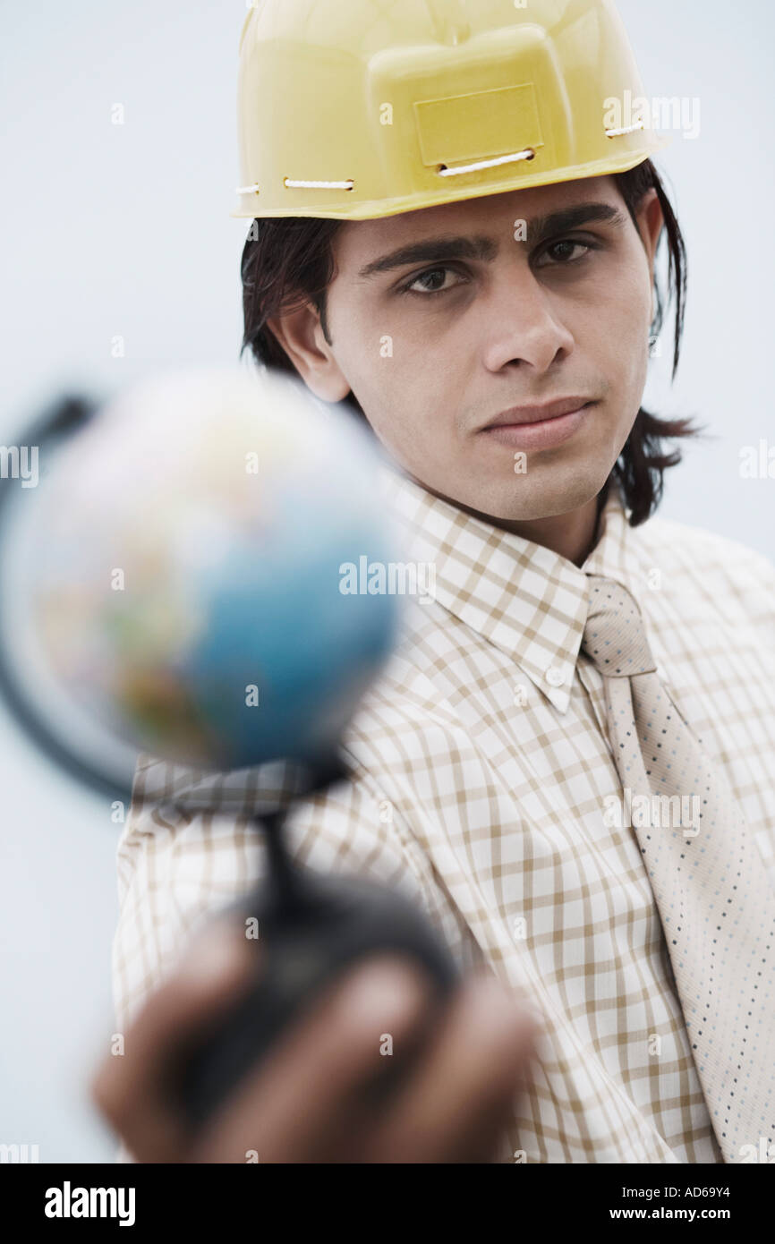 Portrait of an architect wearing a hardhat holding a globe Stock Photo