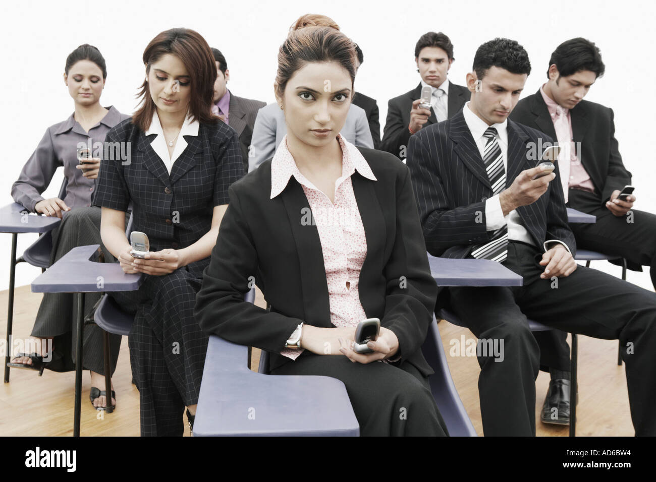 Business executives sitting on chairs holding mobile phones Stock Photo