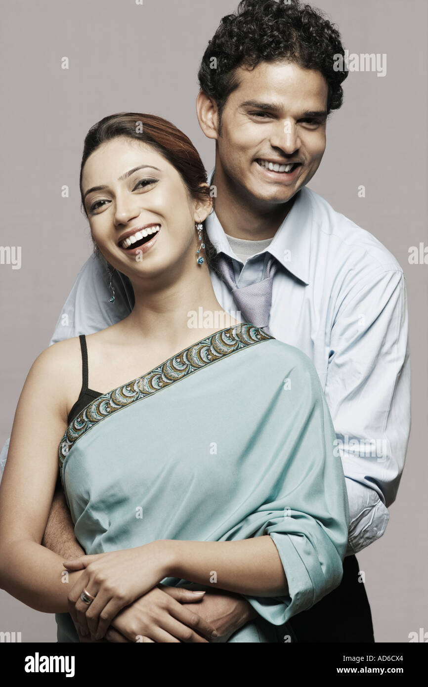 Portrait of a young man embracing a young woman from behind Stock Photo ...