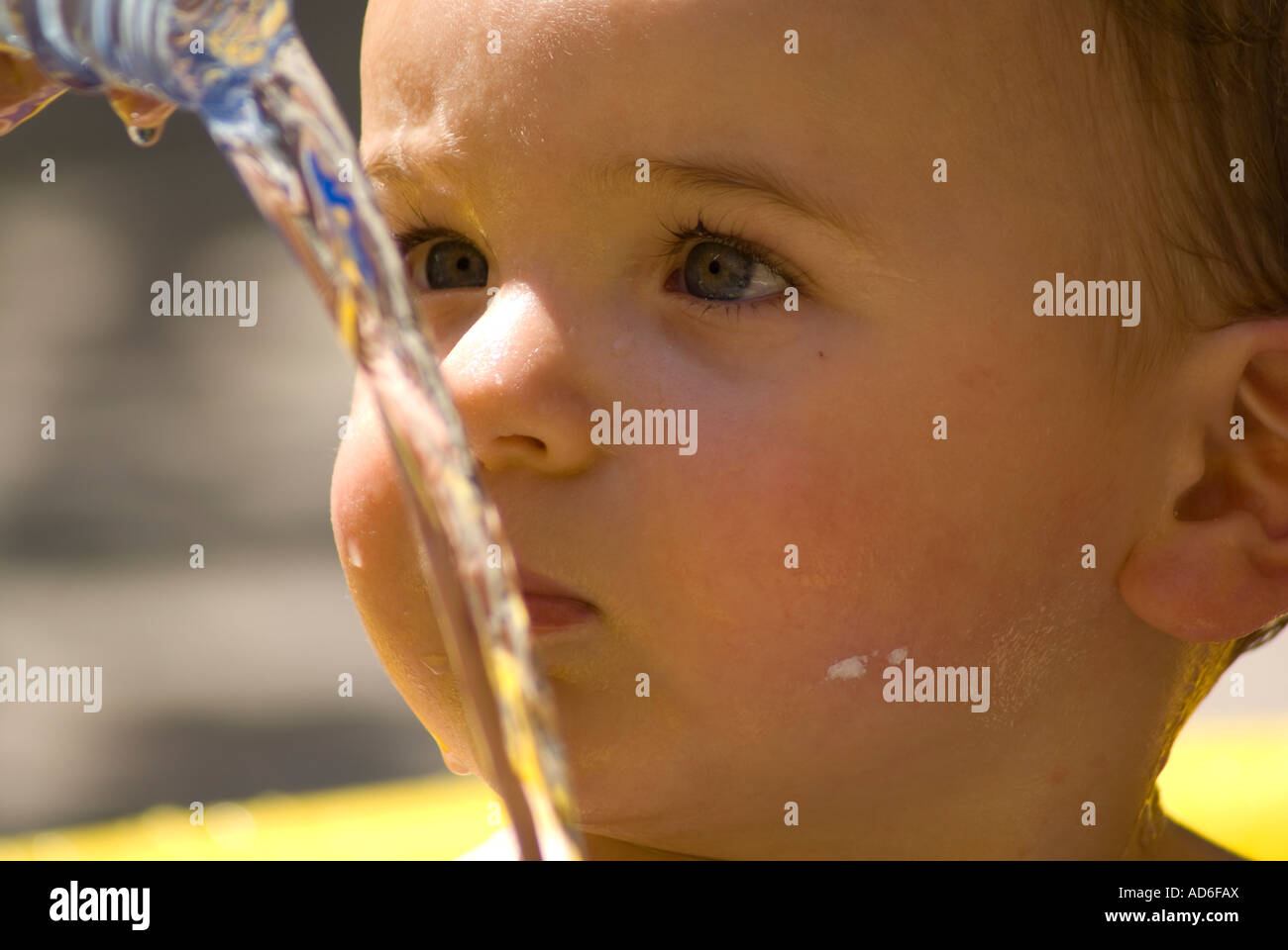 One year old baby playing with water in the swimming pool Stock Photo
