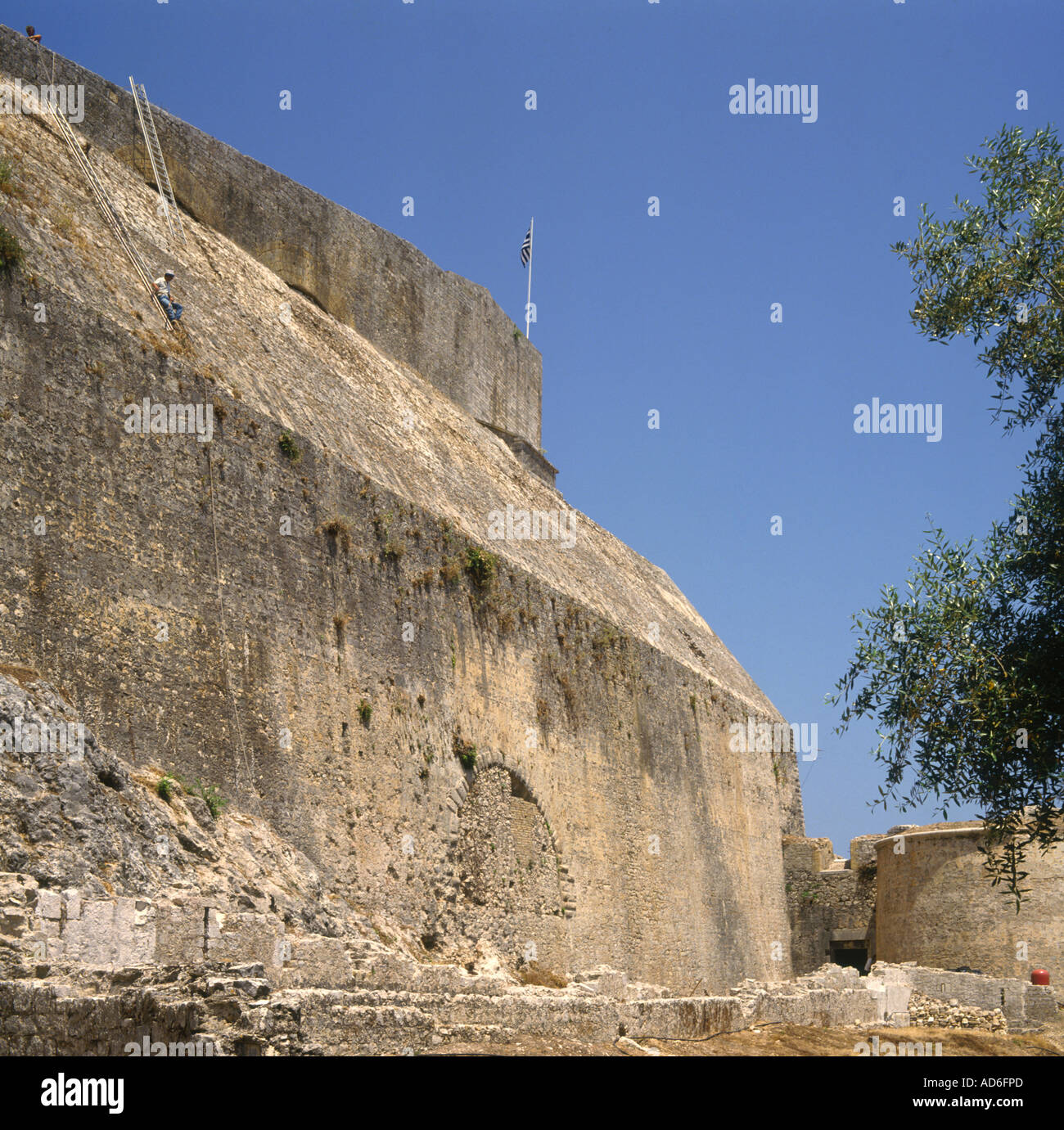 Man cleaning steep stone walls of The New Fort with ladders ropes and flag Corfu The Ionian Islands Greek Islands Greece Stock Photo