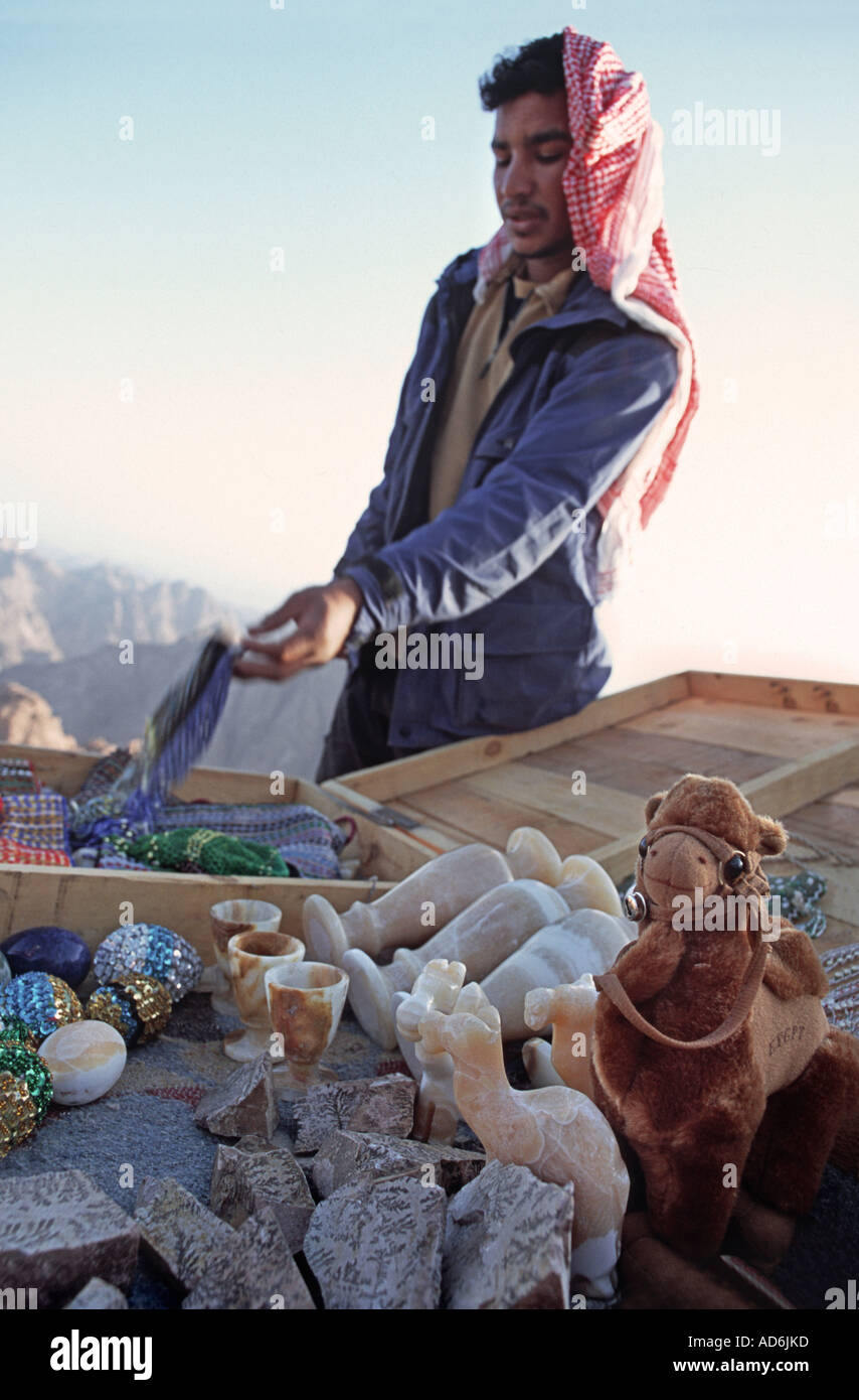 Bedouin trader at the summit of mount Sinai vending souvenirs including a stuffed toy camel and stone carvings Sinai Egypt Stock Photo