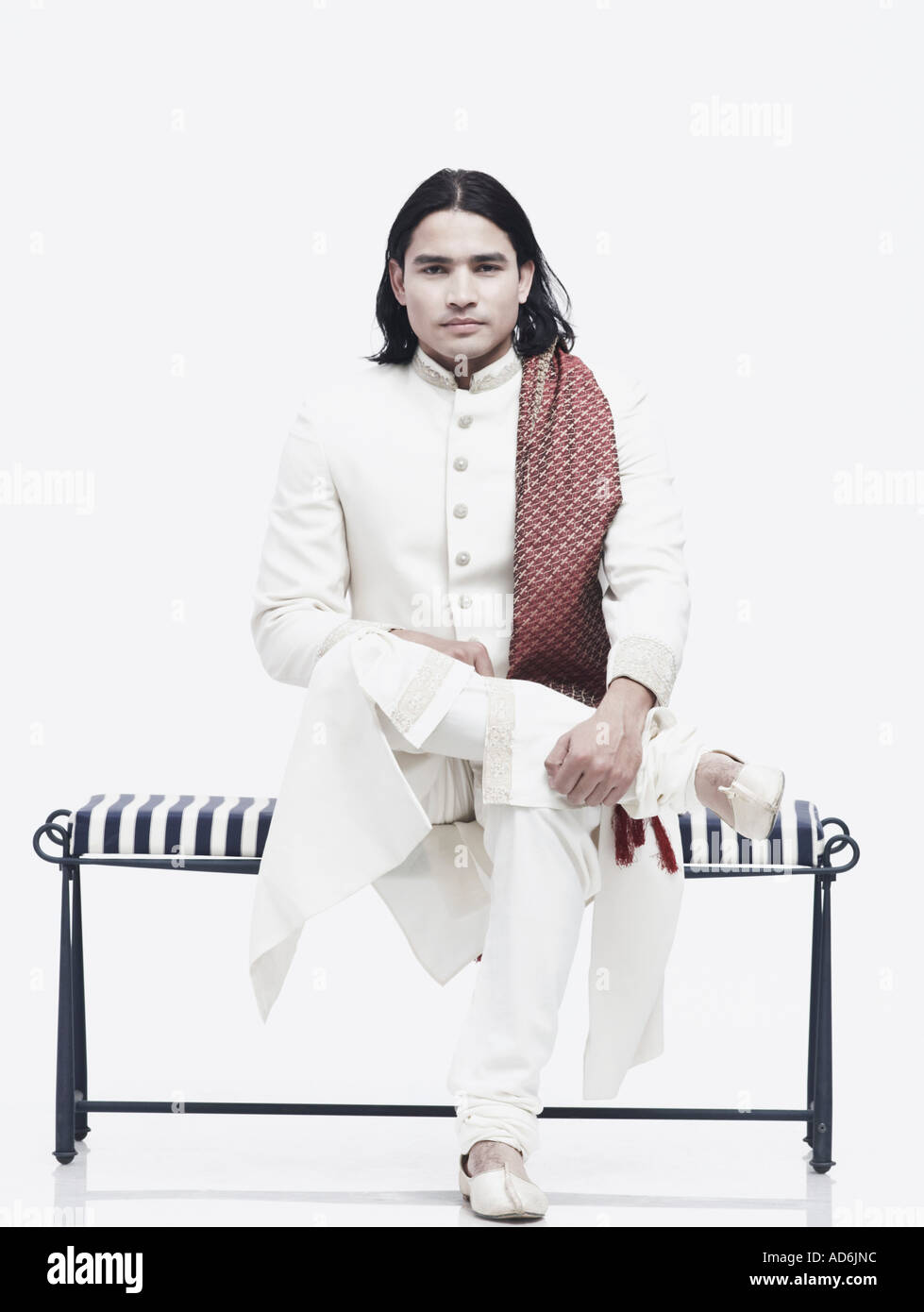 Portrait of a young man in traditional clothing sitting on a bench ...