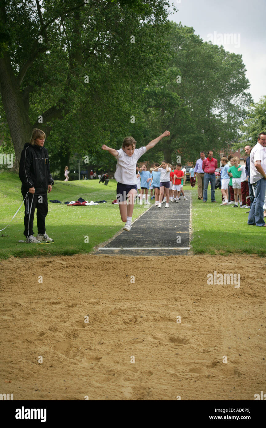 Eight year old pupil taking part in long jump event during sports day