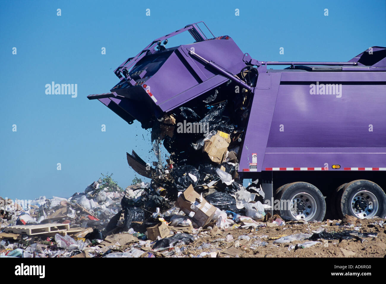 A large garbage truck dumps trash at a landfill Stock Photo