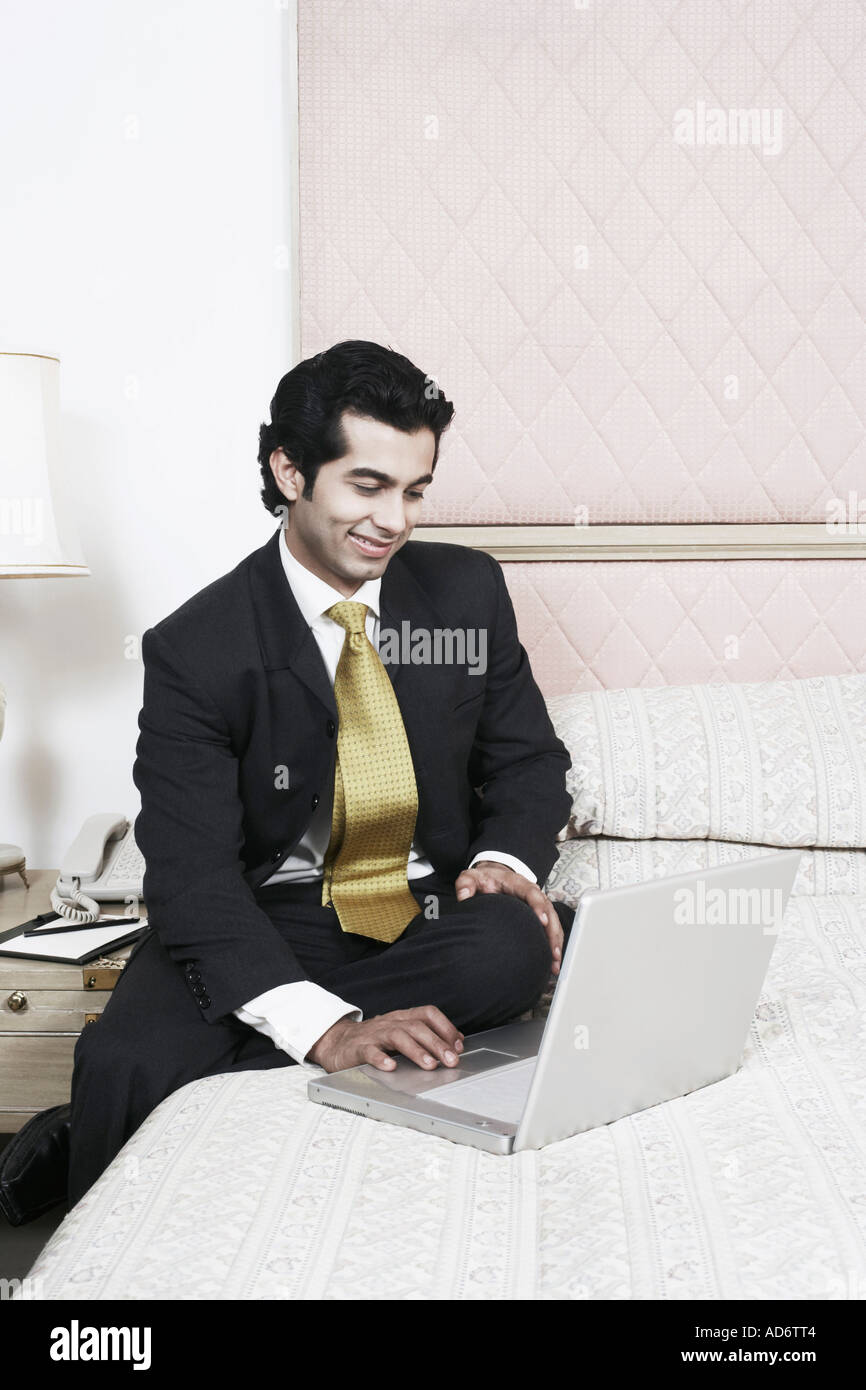 Businessman sitting on the bed using a laptop Stock Photo