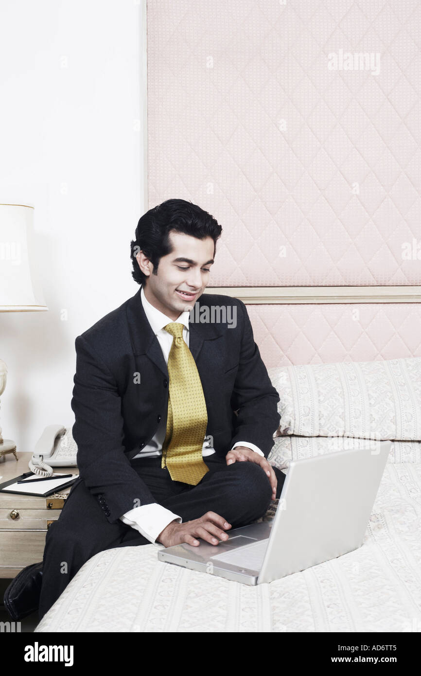 Businessman sitting on the bed using a laptop Stock Photo