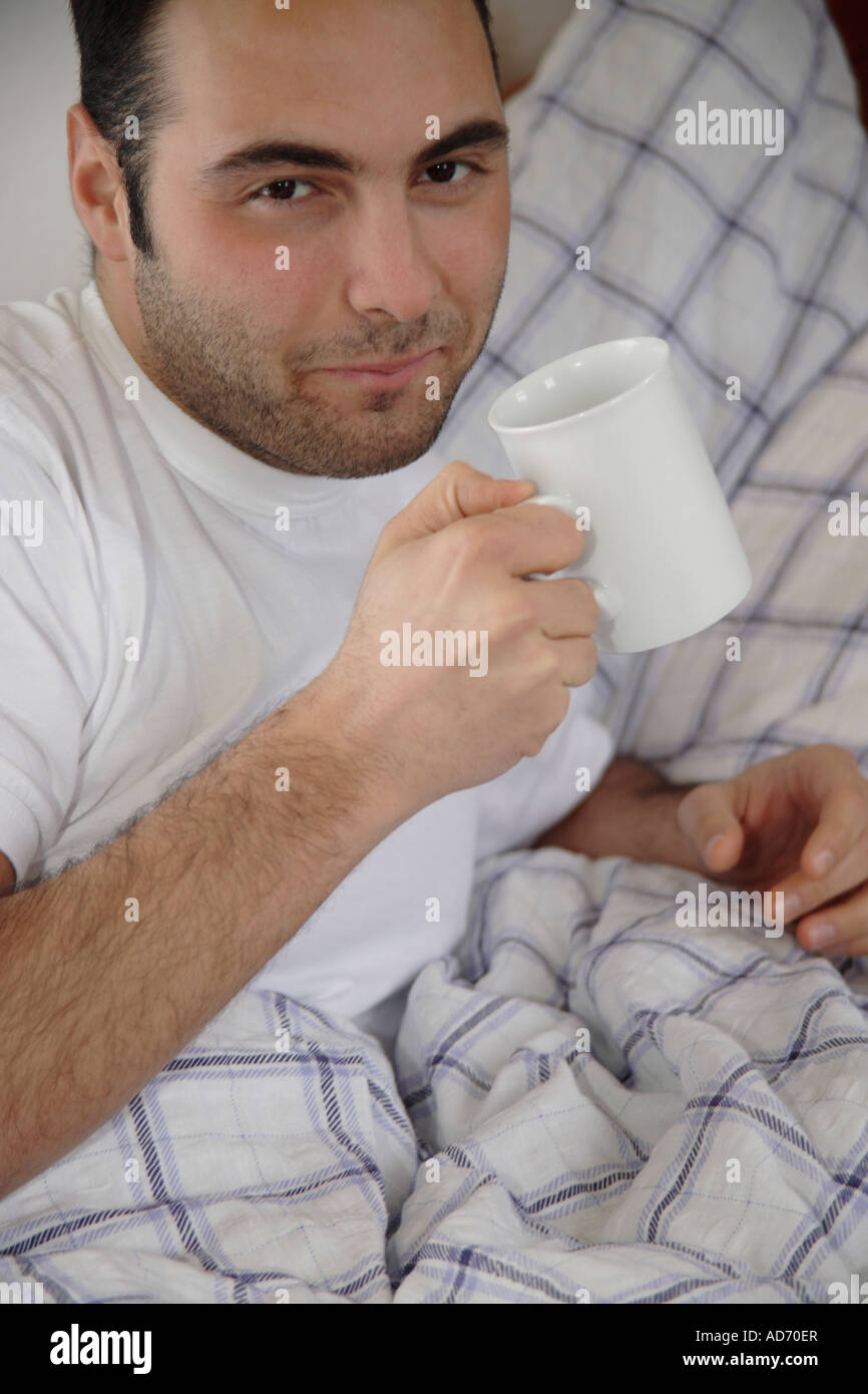 Young man drinking coffee in bed Stock Photo Alamy