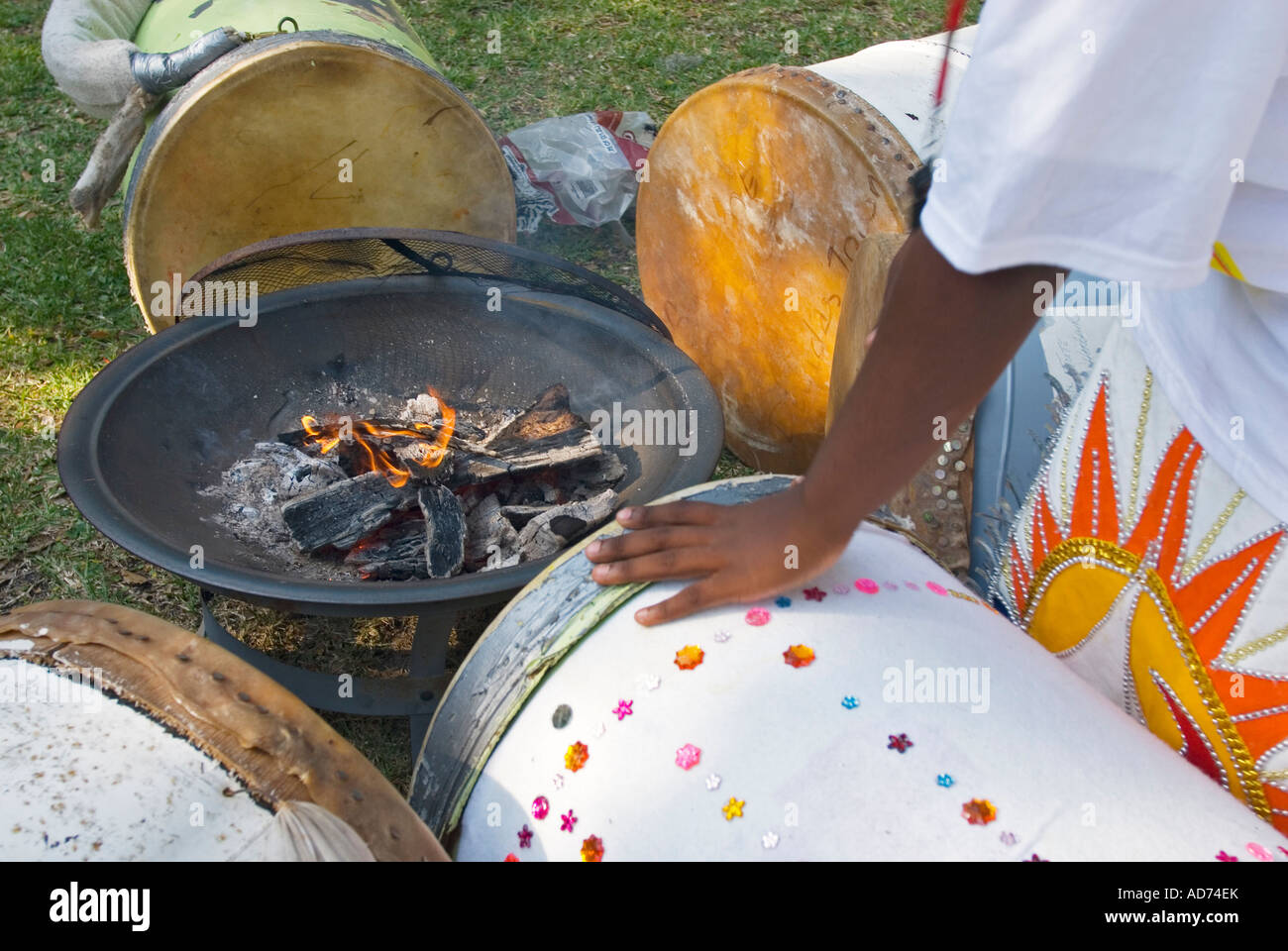 Participant in a Bahamian junkanoo parade preparing drums by heating the skins by a fire Stock Photo