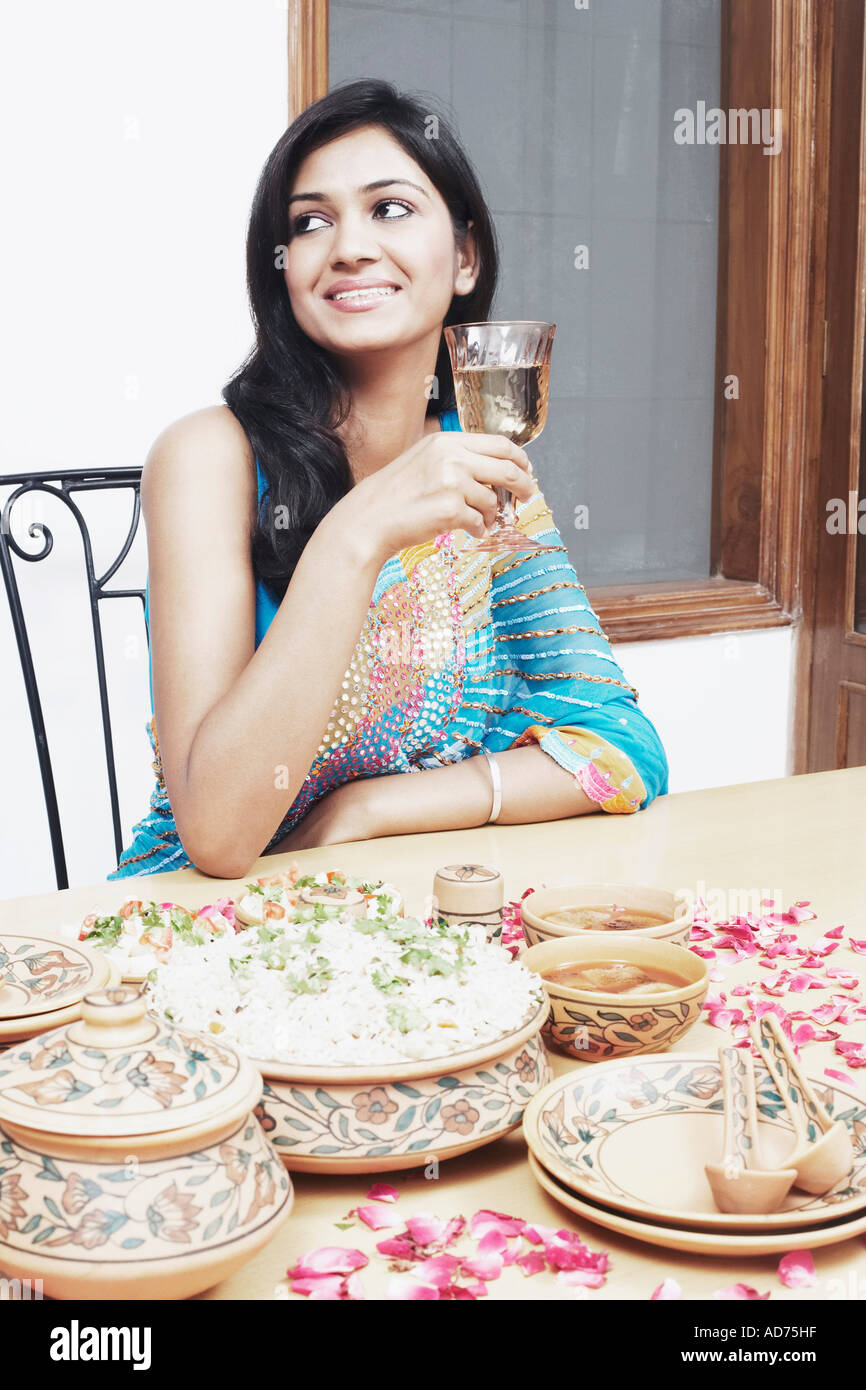 Young woman sitting at a table holding a glass of wine Stock Photo