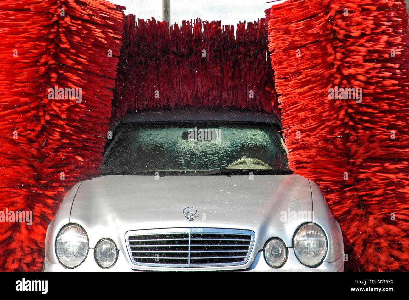 Silver Mercedes is being washed with red brushes at the car wash Stock