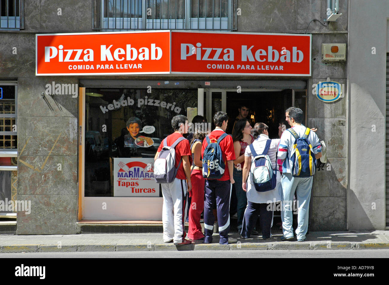 School children with rucksacks jostleling into the door of a pizza and kebab shope, Elx, Elche, Costa Blanca, Spain Stock Photo