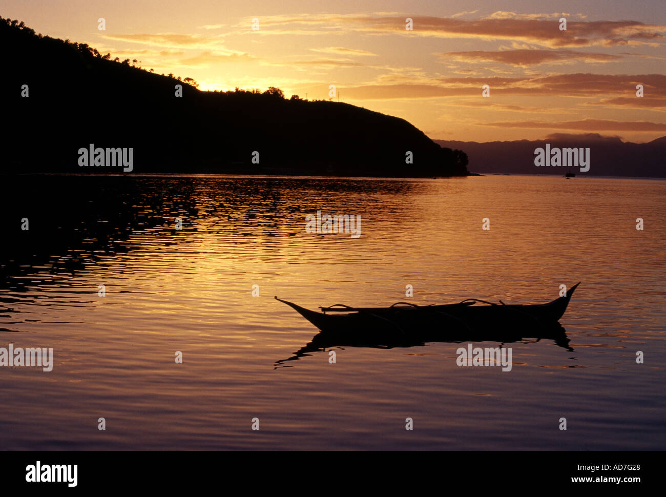 Boat was floating on a bay that was reflecting a beautiful sunset in Romblon, Philippines. Stock Photo