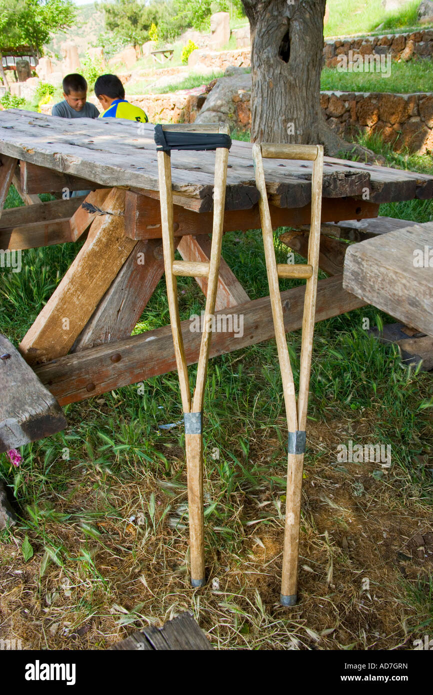 A pair of old crutches leant against an old wooden picnic table with two  local boys at the background Yesemek Village Islahiye G Stock Photo - Alamy