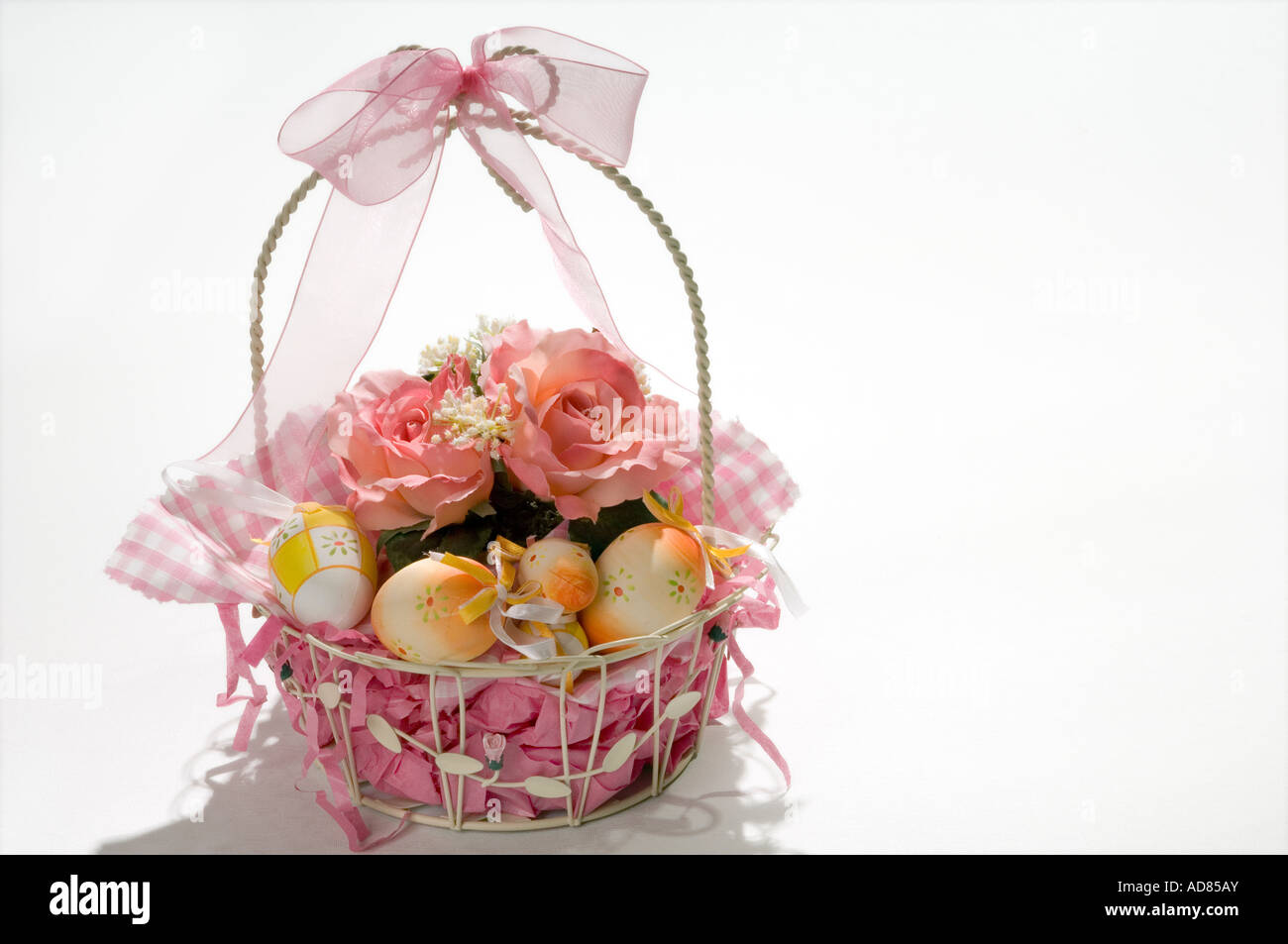 Easter basket with eggs and silk flowers against white studio background Stock Photo