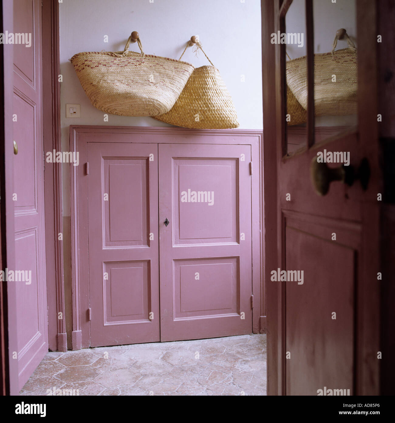 Country house entrance with pink panelling and straw baskets Stock Photo