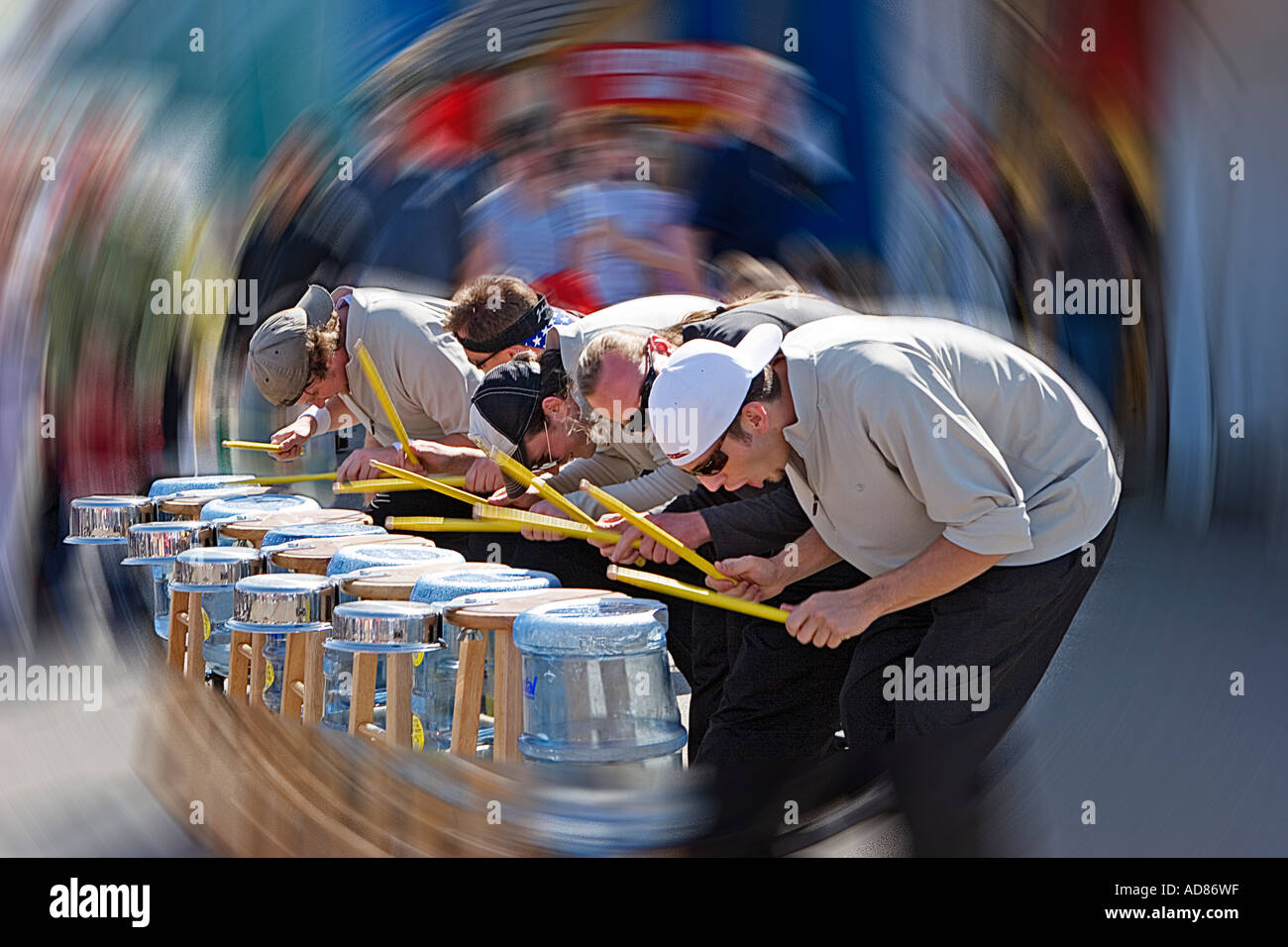 Photograph of a group of street musicians playing drums made from pots pans waterbottles at the