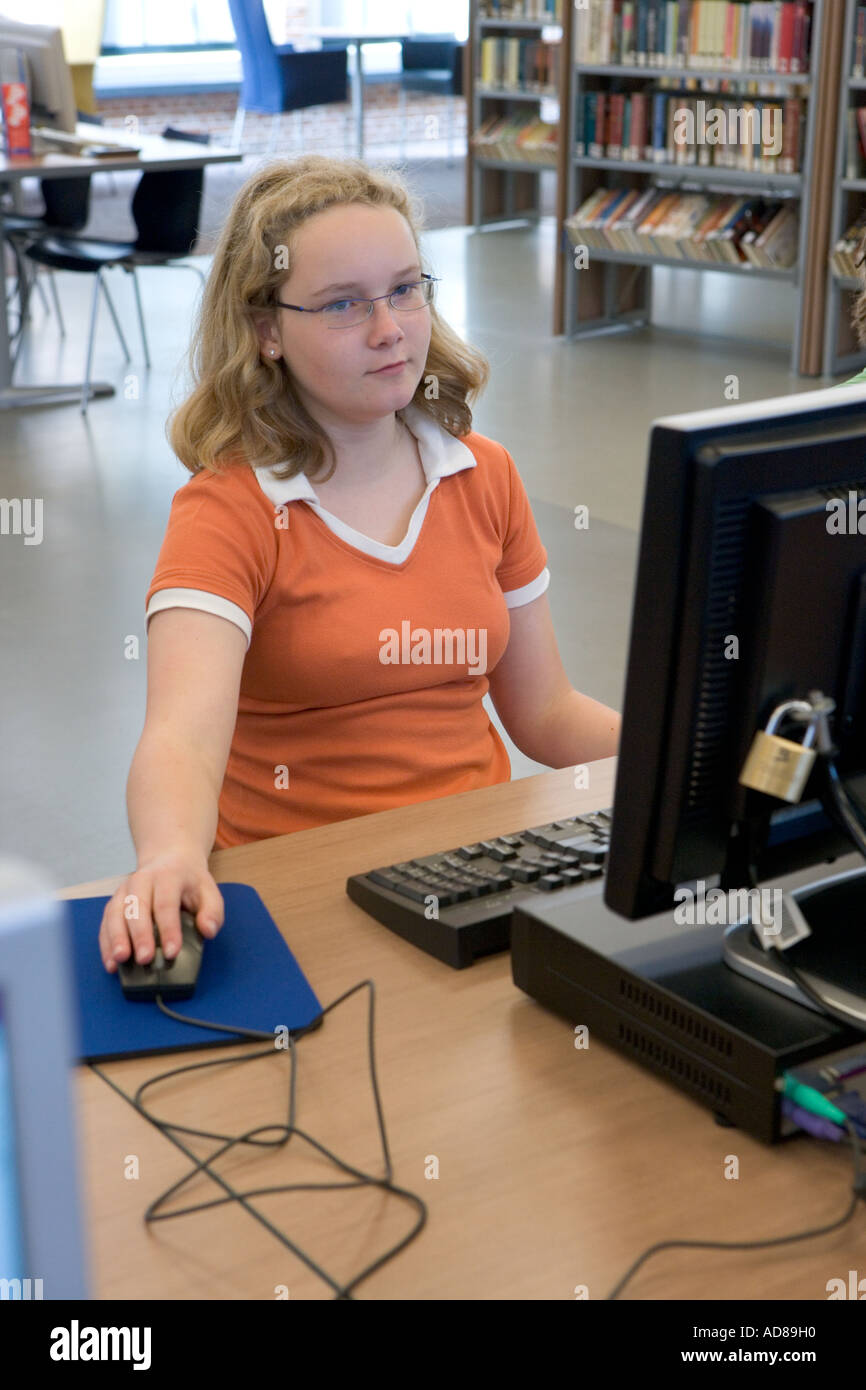 Teenage girl behind a computer in the library Stock Photo - Alamy