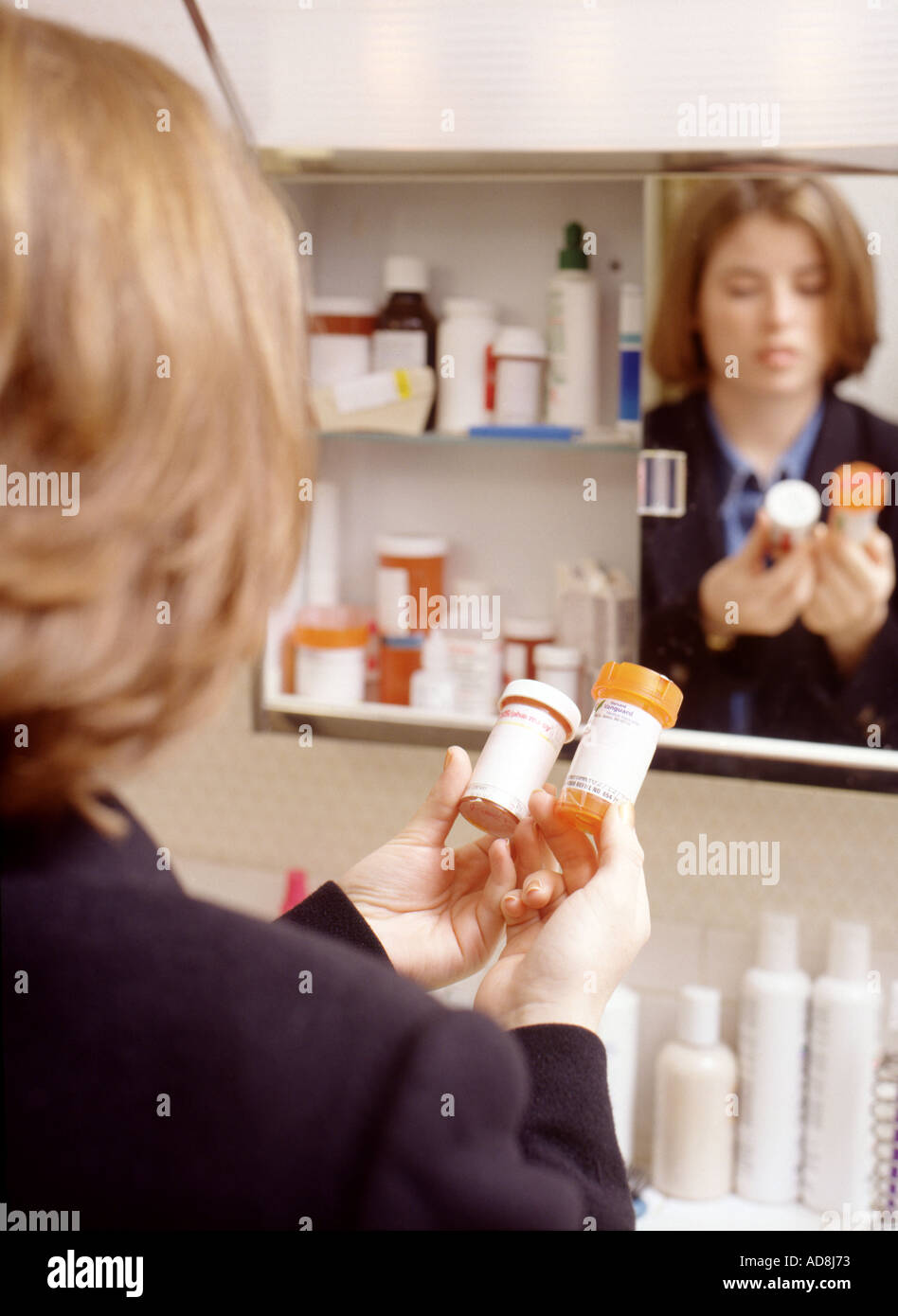 Closeup of young woman looking at prescription medicine in bathroom