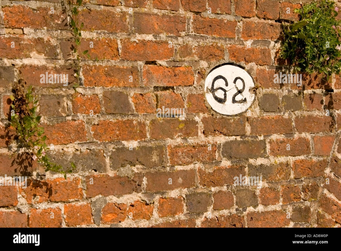 No 62 painted on an old brick wall next to a canal bridge Stock Photo