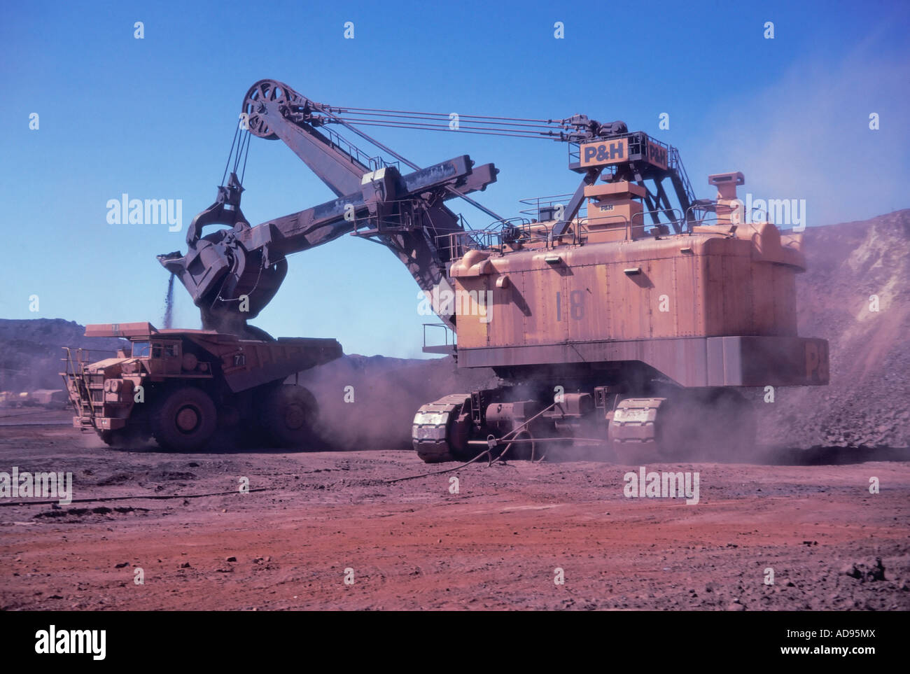 Huge electric shovel loads iron ore onto a Haulpak truck at Mt Newman mine in NW Australia Stock Photo