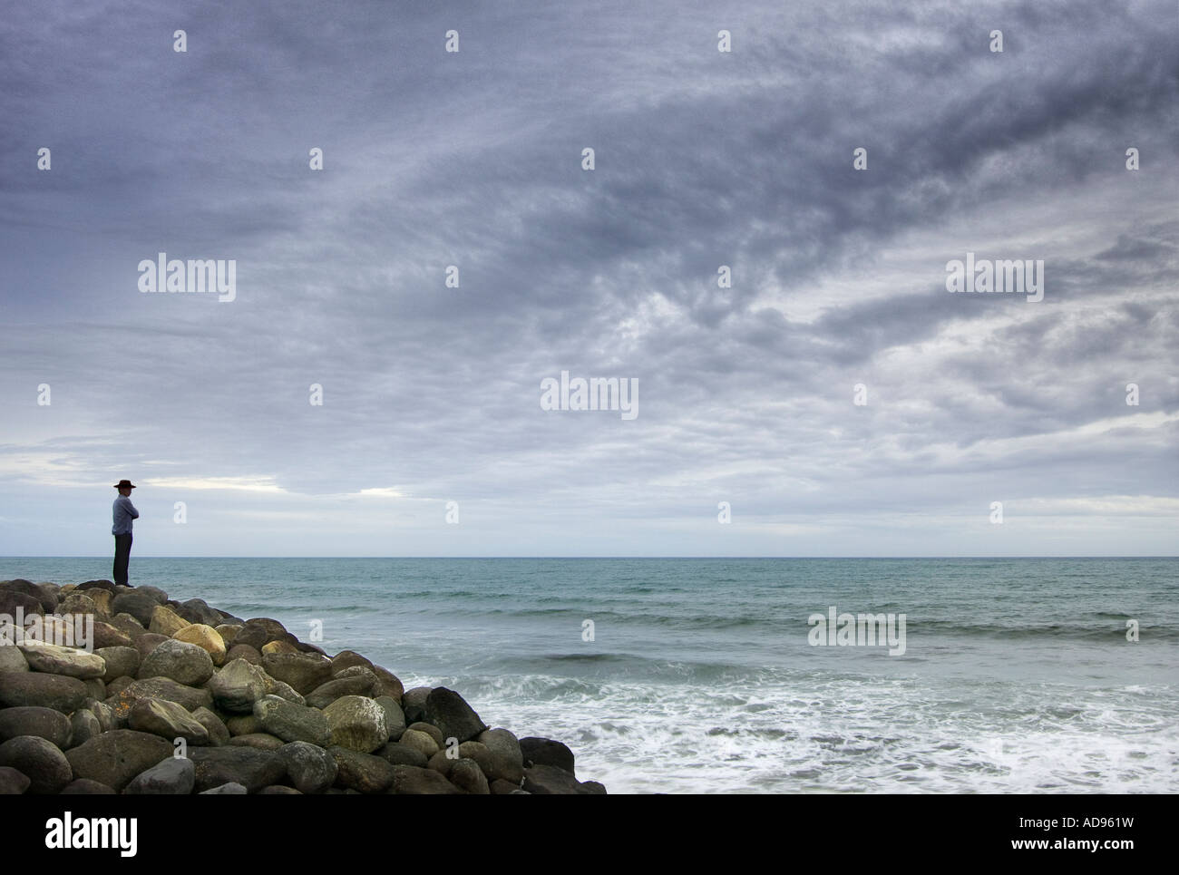 A lone figure looks out to sea Stock Photo