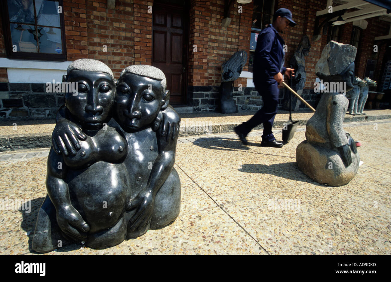 A cleaner walks past stone sculptures at the Victorai and Alfred waterfront, Cape Town, South