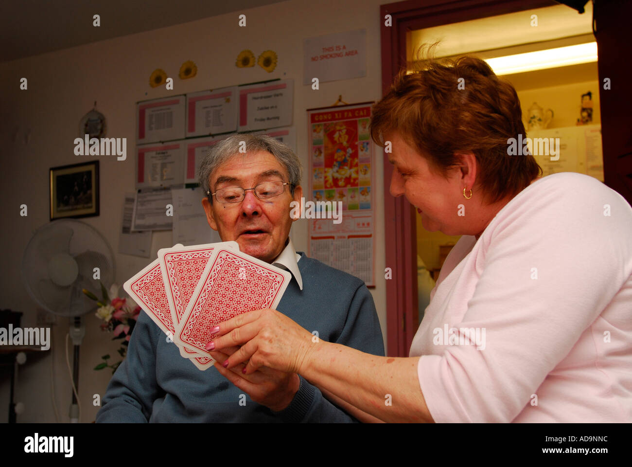 Member of care staff playing cards with elderly resident at care home