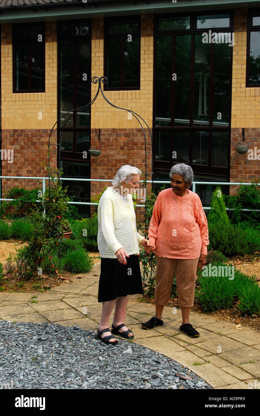 Two elderly residents of care home for dementia sufferers walking in